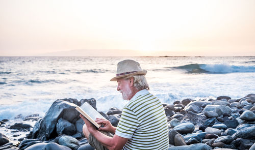 Man standing on rock at beach against sky