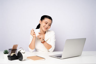 Young woman using mobile phone while sitting on table