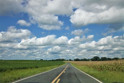 Straight road under puffy clouds