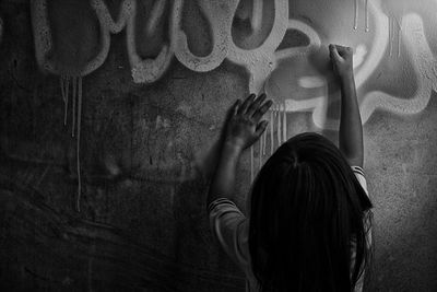Rear view of girl writing on wall