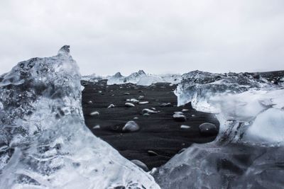 Ices at diamond beach against sky in winter