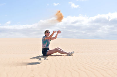 Man with umbrella on sand in desert against sky