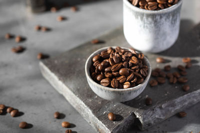 Roasted coffee beans in a bowl on a gray board.