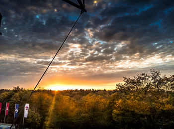 Silhouette trees against dramatic sky during sunset