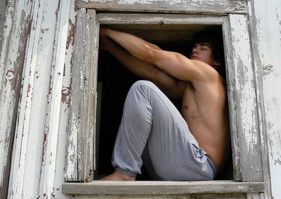 Midsection of man sitting on wood window