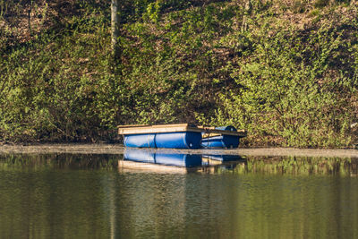 Boat moored in lake against trees in forest