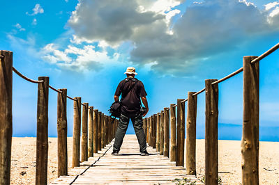 Man standing on railing against sea