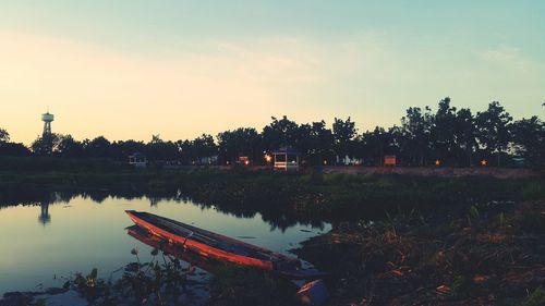 Scenic view of lake by trees against sky during sunset
