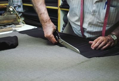 Midsection of man working with scissors on table