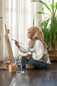 Side view of young woman sitting on table