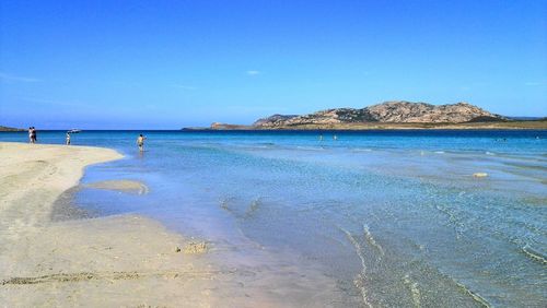 Scenic view of beach against clear blue sky