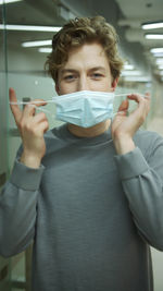 Portrait of young man wearing surgical mask at office