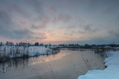 Scenic view of frozen lake against sky during sunset