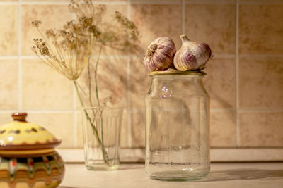 Close-up of garlic bulbs over jar on table