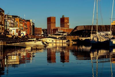 Sailboats moored in harbor against buildings in city