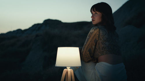 Girl thinks and imagines near a rock at night