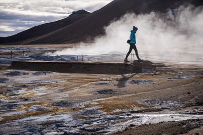 Woman walking by hot spring against mountain