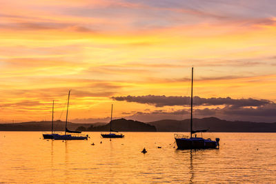 Sailboats in sea against sky during sunset