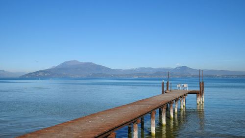 Pier over lake against blue sky