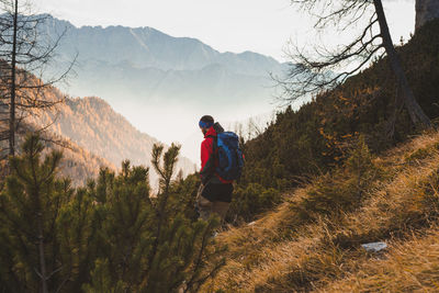 Rear view of man walking on mountain against sky