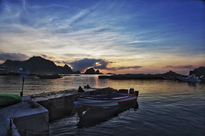 Boats moored on sea against sky during sunset