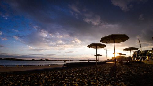 Scenic view of beach against dramatic sky during sunset