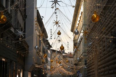 Low angle view of christmas decorations hanging amidst buildings