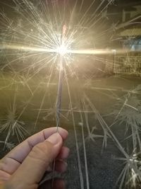 Midsection of person holding sparkler at night