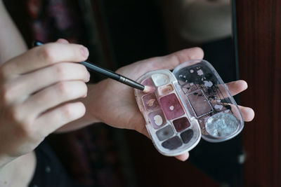 Midsection of woman holding paintbrush with palette 