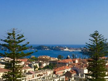 Town by sea against clear blue sky