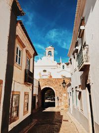 Alley amidst buildings against blue sky