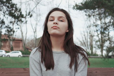 Close-up portrait of young woman against trees