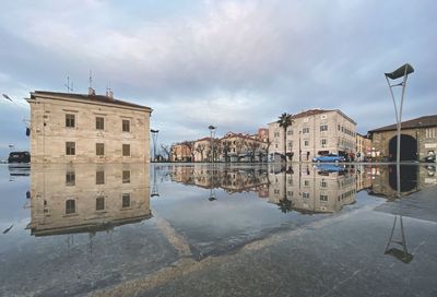 Buildings by river against sky in city