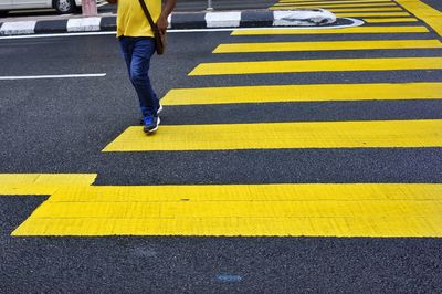 Low section of person walking on zebra crossing