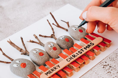 Diy merry christmas deer on greeting card postcard made of pebbles, sea stones, clothespins 