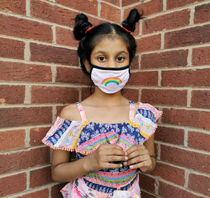 Portrait of girl standing against brick wall