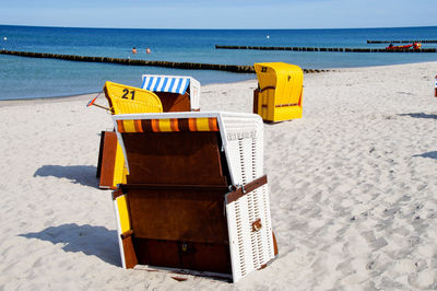 Hooded chairs on sand against sea at beach