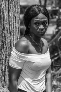 Ghana woman leans against a tree in accra and has a worried facial expression