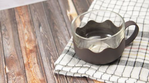 An empty cup that made from clear glass and plastic handle on a wooden background