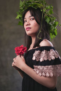 Beautiful young woman holding flower in standing at home