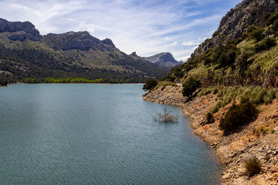 Scenic view of river by mountains against sky