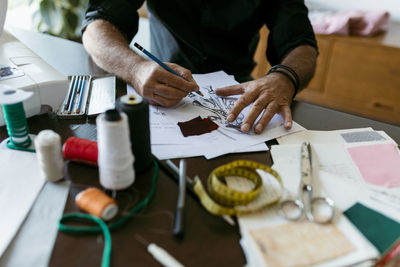 Mature costume designer sketching outfit on paper in studio