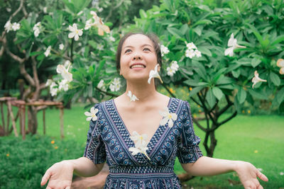 Smiling woman looking at falling flowers in park