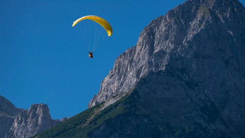 Low angle view of person paragliding against sky