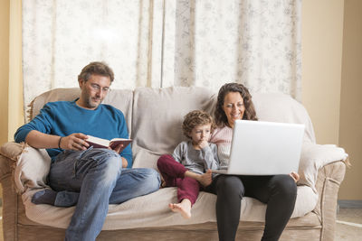 Family sitting on sofa at home