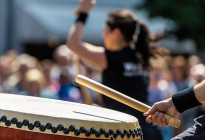 Midsection of artist playing drum against crowd