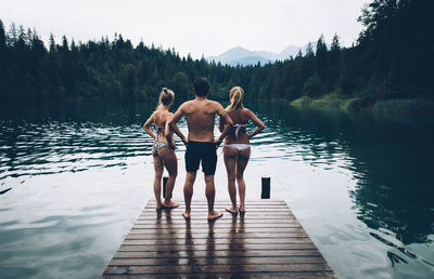 Rear view of people standing by lake