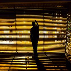 Rear view of silhouette man standing against illuminated building