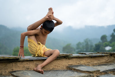 Man sitting on wood against sky