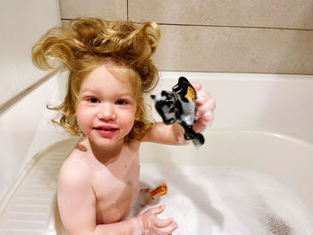 High angle view of young child in bathtub holding a toy